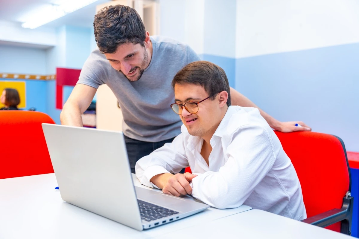 Man using a laptop with a support coordinator beside him